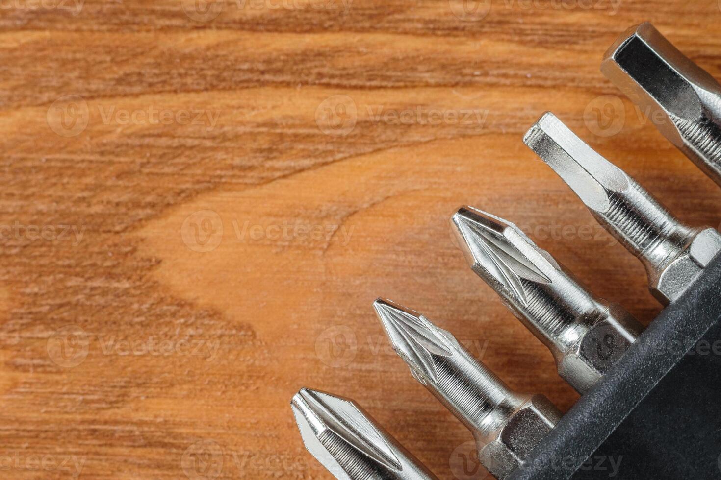 A set of tools collection from heads for screwdriver or bits on a wooden table with copy space. Flat lay. Corner arrangement. photo