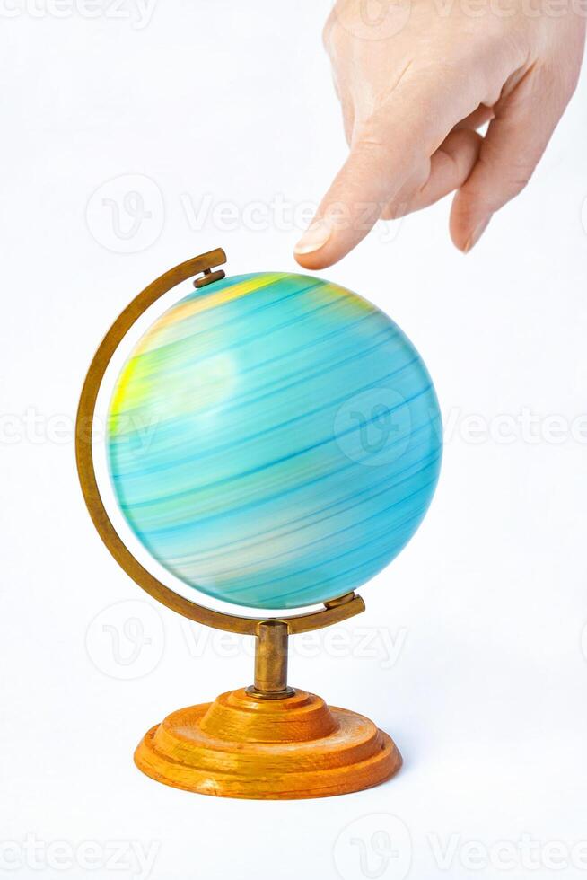 Female hand pointing to a rotating globe. The funny concept of choosing a place to relax or travel photo