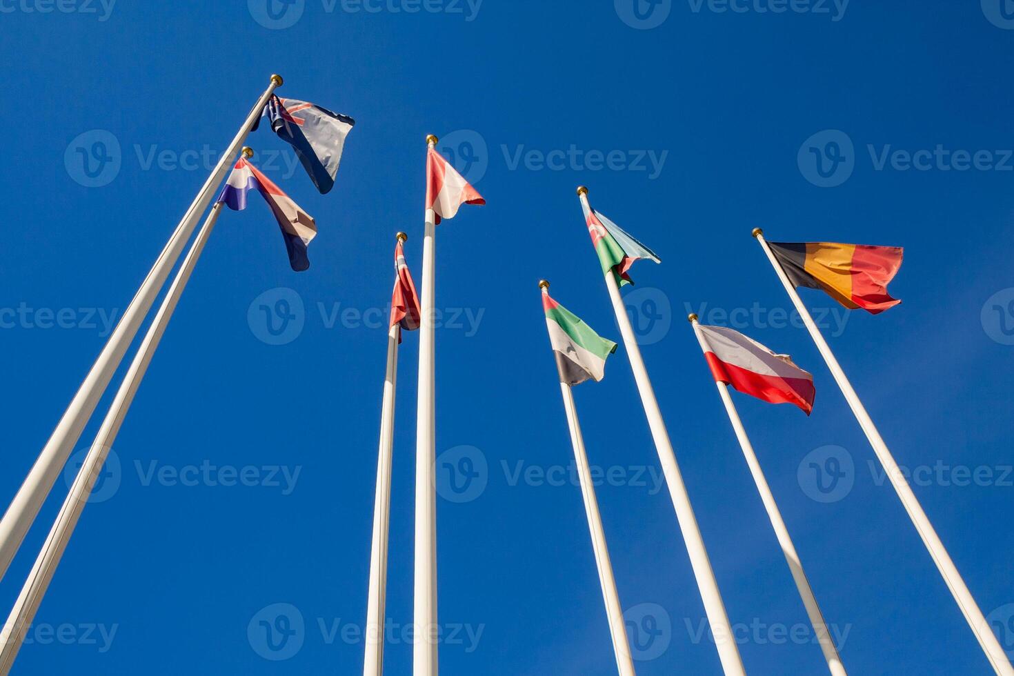 Bottom view of a flags of different countries against a clear blue sky photo