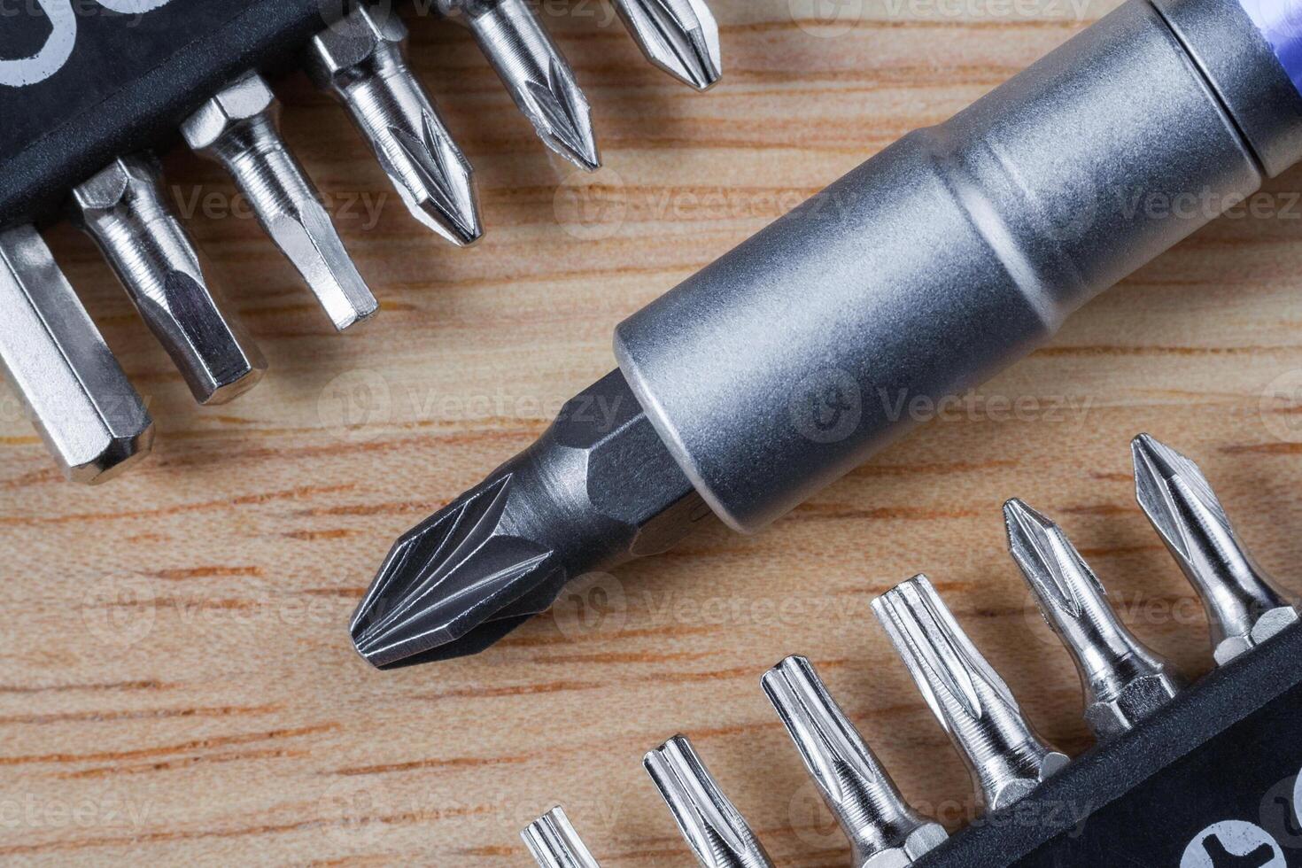 Set of heads or bits and screwdriver on a wooden table photo