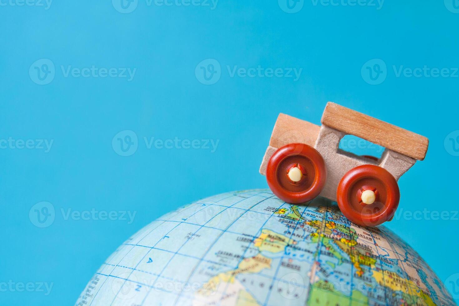 Wooden toy car on a globe on azure background with copy space. The concept of tourism, travel photo
