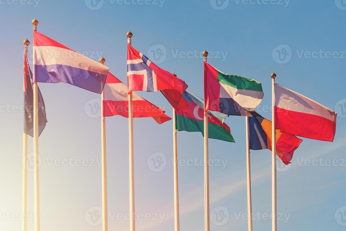 Flags of different countries of the world flutters in the wind against a sunlight photo