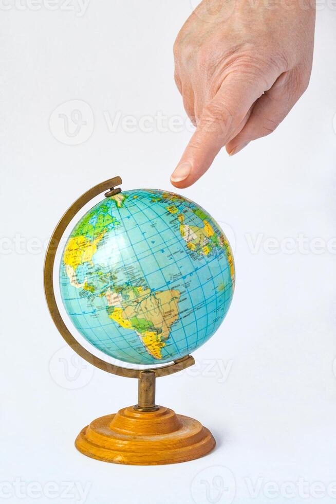 Female hand pointing to a globe. The concept of choosing a place to relax or travel photo