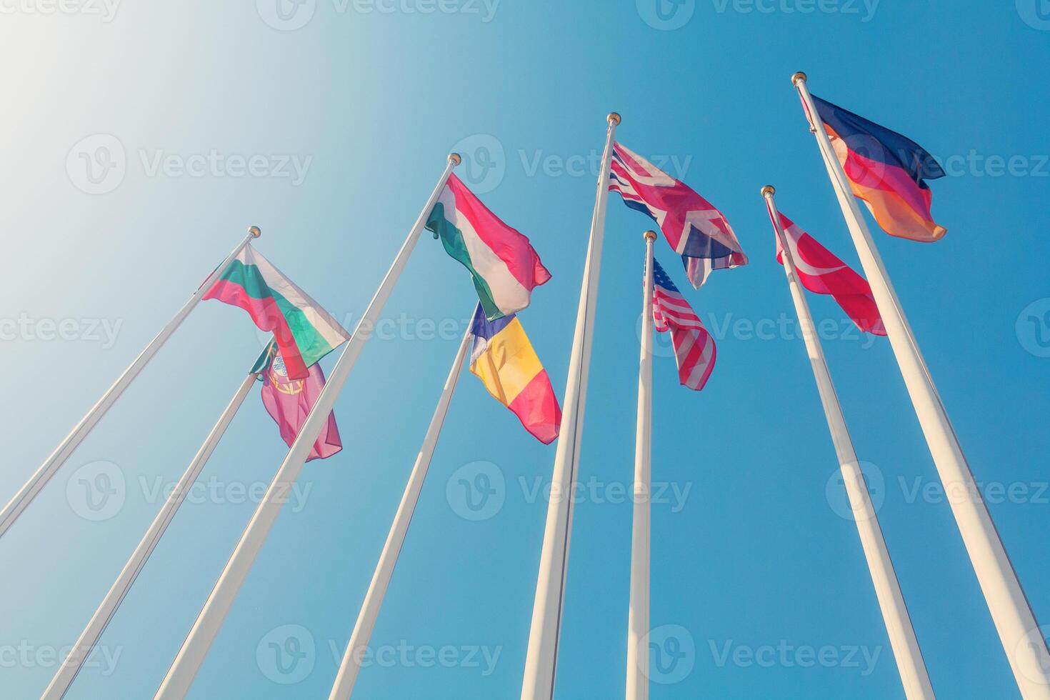 Bottom view of a flags of different countries of the world against a sunlight in the clear blue sky photo