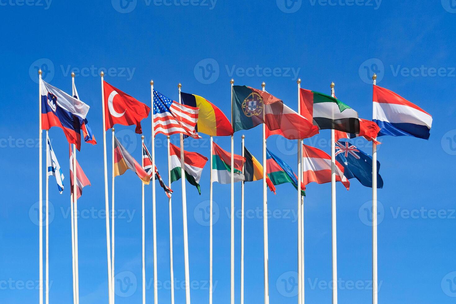 Flags of different countries of the world flutters in the wind a background of clear blue sky photo