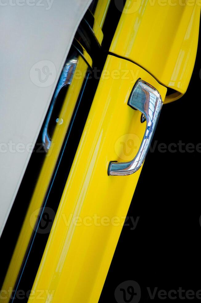 Top view of the door of a yellow car with a chrome handle on a black background. Exhibition of retro cars. photo