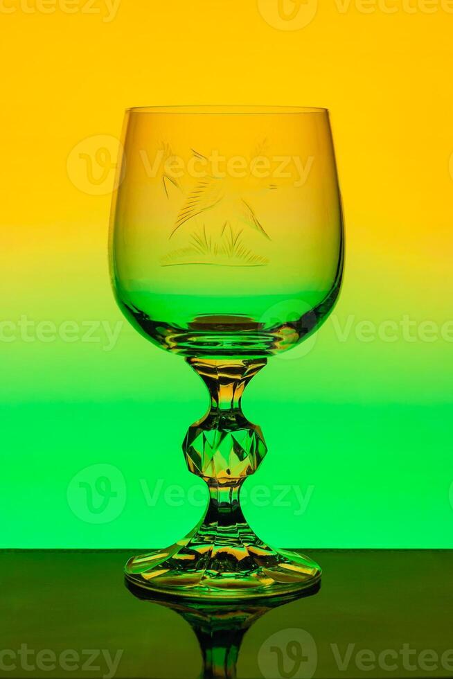 Crystal wine glass with engraved pattern on a background of multi colored gradient photo