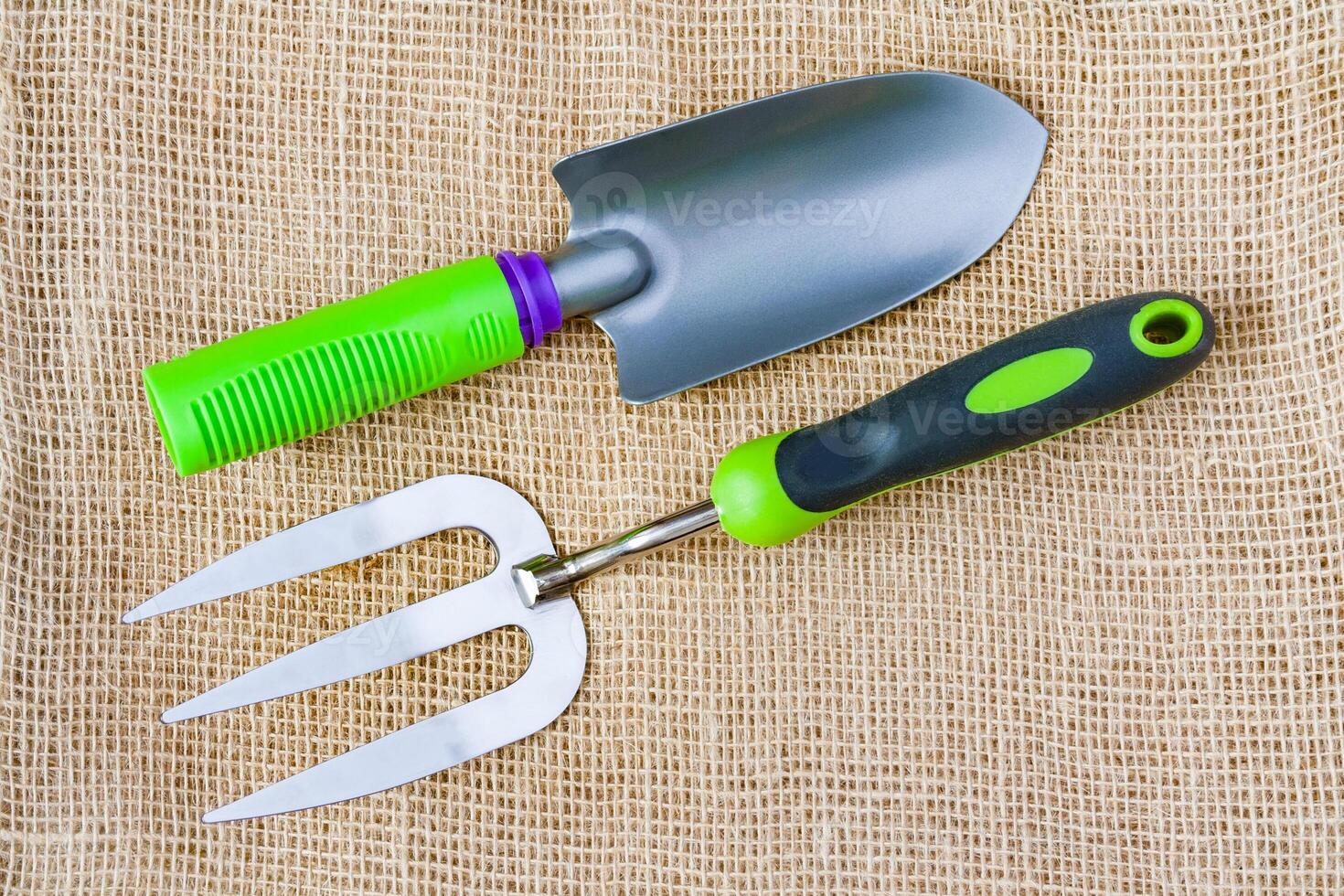 Small garden tools planting fork, trowel on the sackcloth surface photo