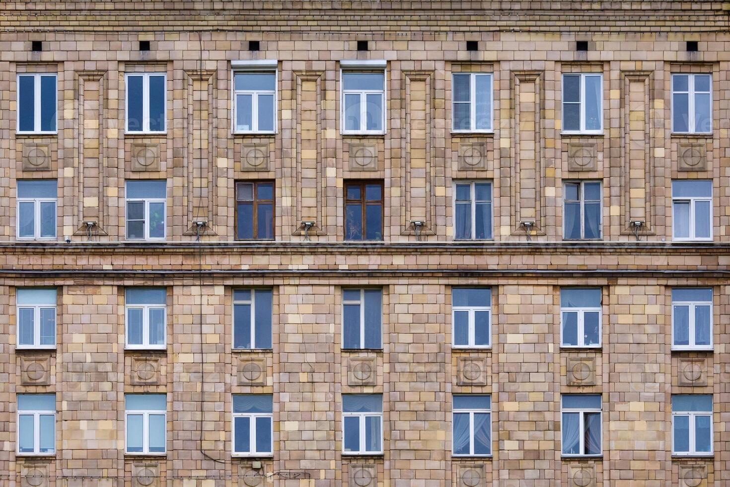 Front view on fragment of facade of a old brick residential building with windows photo