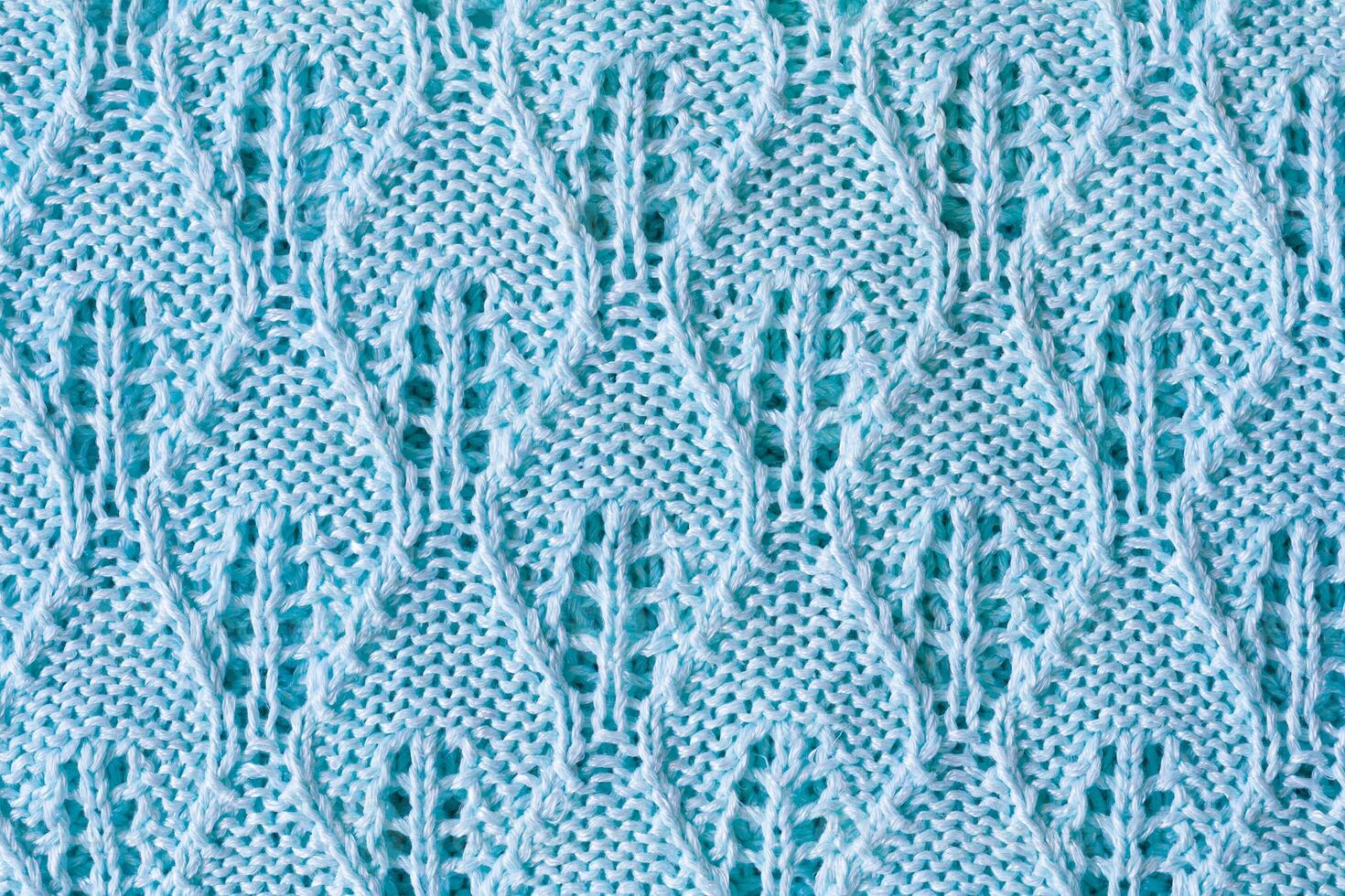 Close up view of a knitted product made from light blue cotton yarn with openwork pattern as texture, background photo