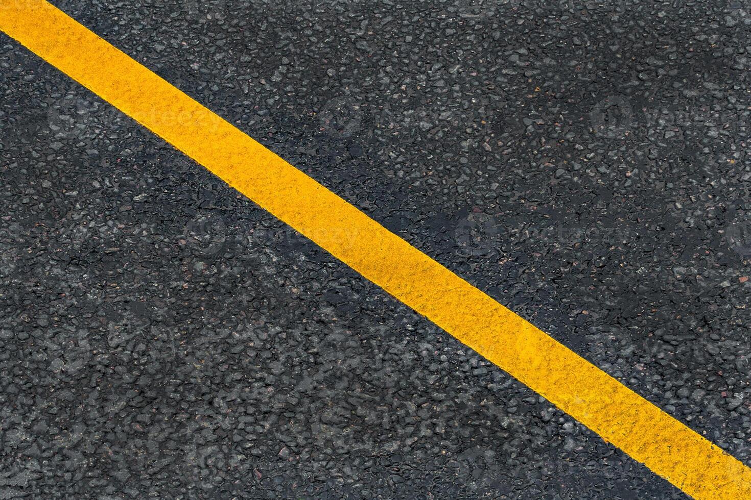 Yellow diagonal marking line on the asphalt road photo