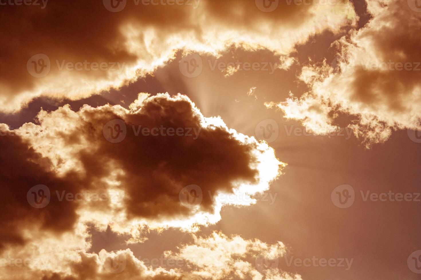 Dramatic view on a orange sky with the sun's rays shining through the dark clouds photo