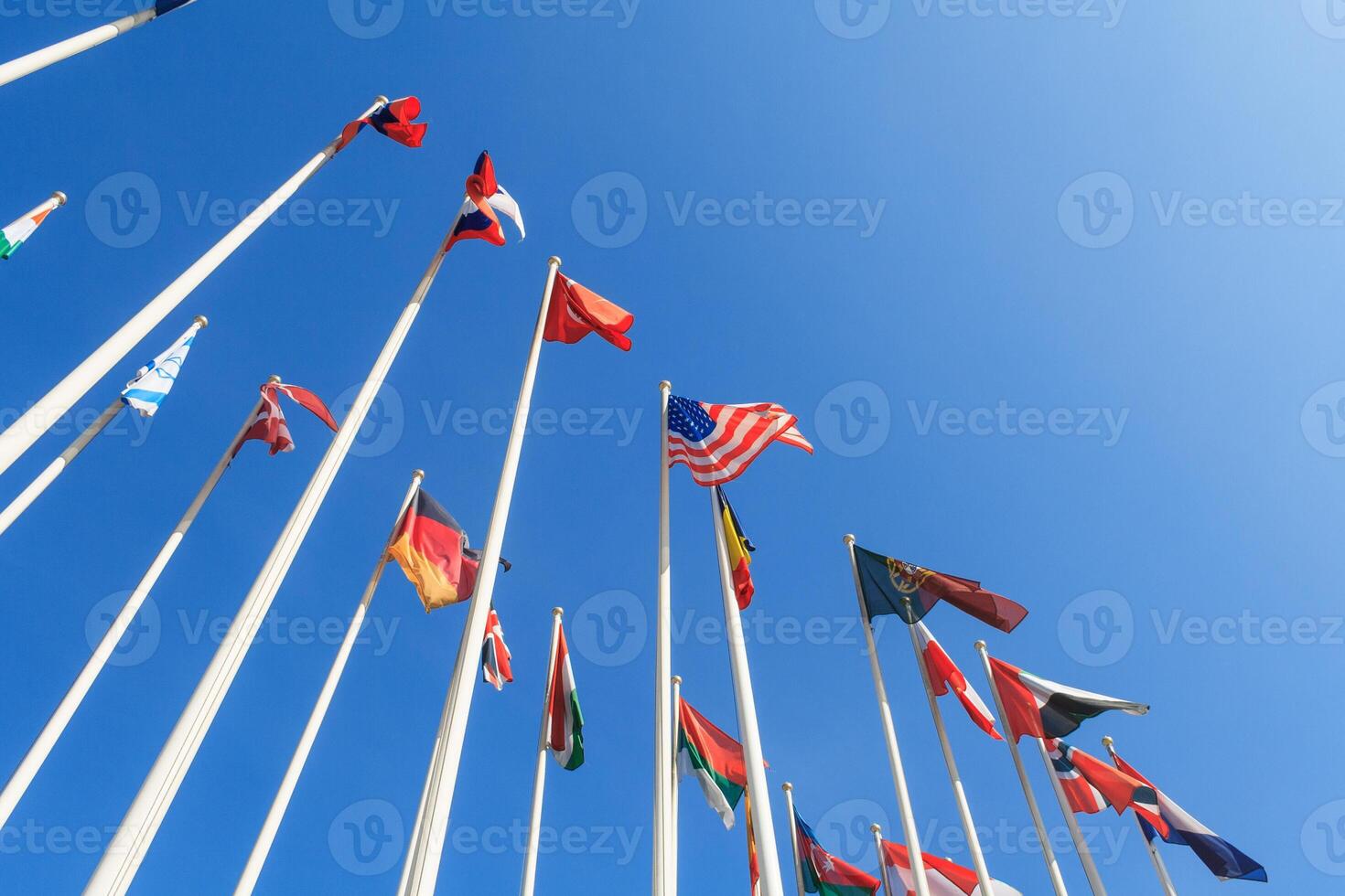 Bottom view of a rows of flags of different countries of the world, flutters in the wind, against a clear blue sky with copy space photo