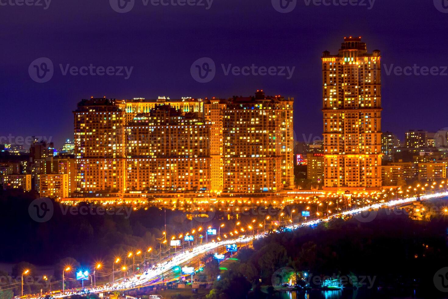 Modern high-rise apartment buildings are illuminated against the background of the evening sky photo