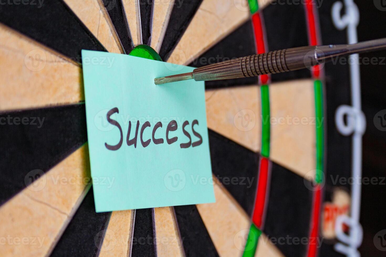 Dart hit the centre of target and attaches sticker with inscriptions success photo