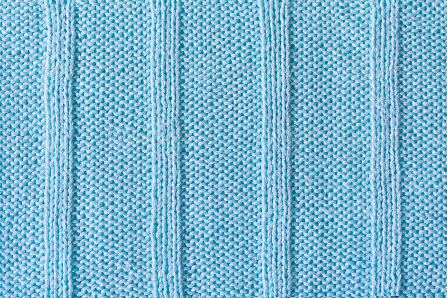 Close up view of a knitted product made from blue cotton yarn, with four stripes as texture, background photo