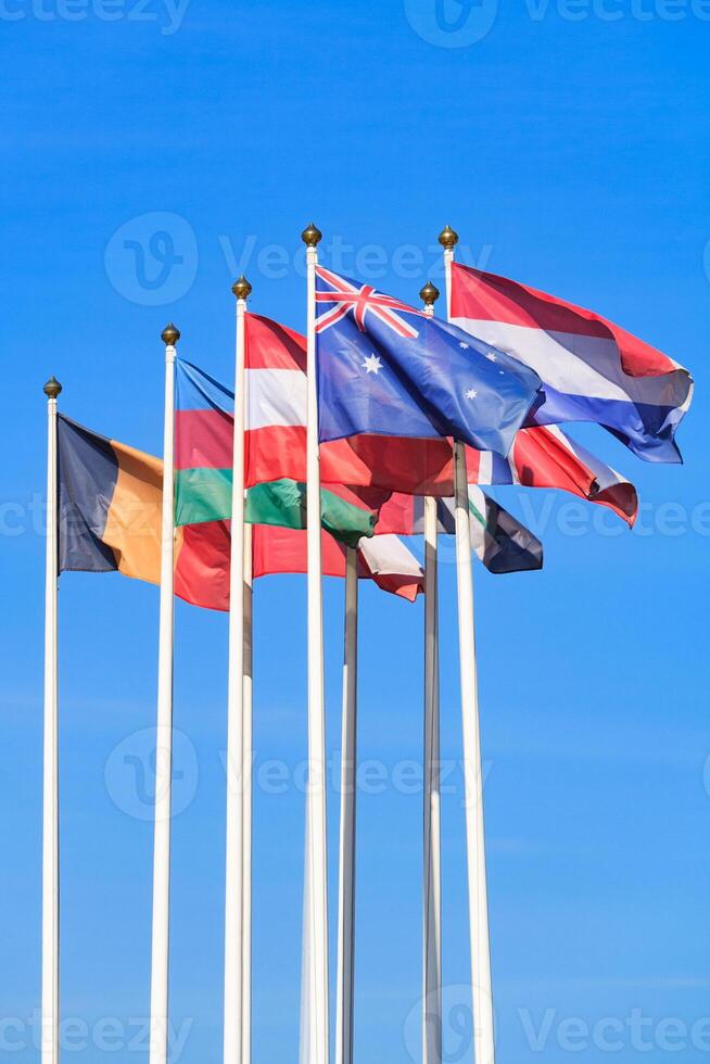 Flags of different countries, flutters in the wind, a background of clear blue sky photo