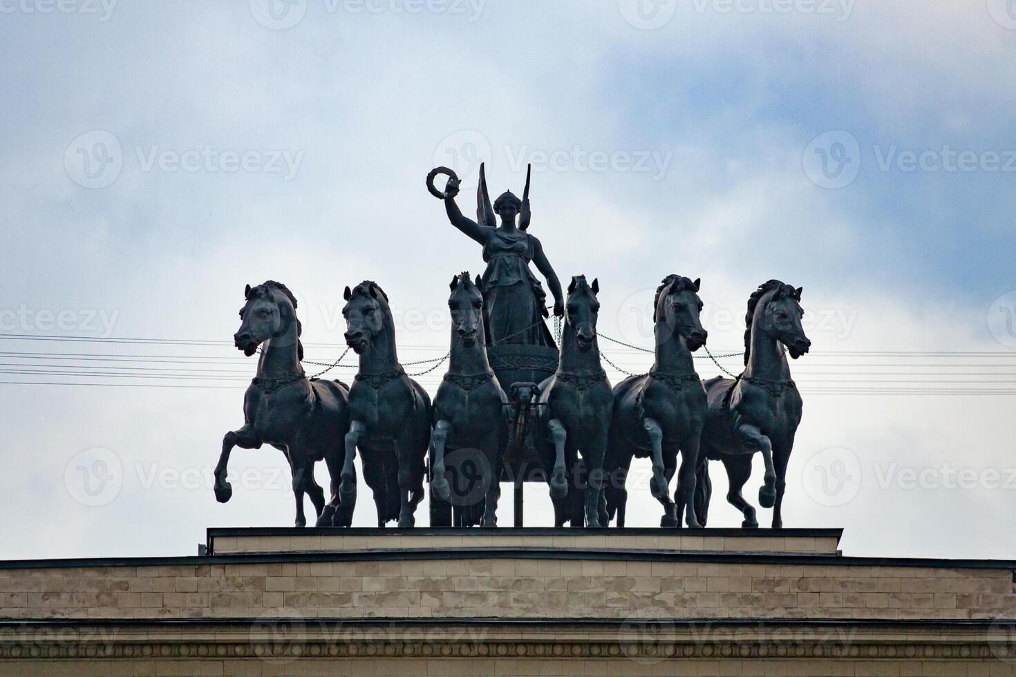 Sculptural group on top of the triumphal arch, six horses with the goddess of victory in the chariot a background of dramatic overcast sky photo