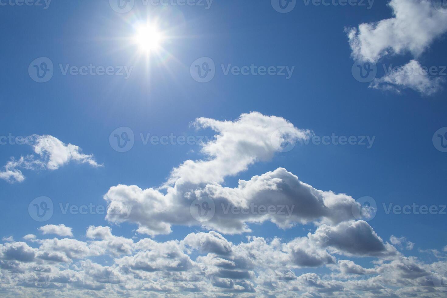 View of a fluffy clouds and midday sun in deep blue sky photo