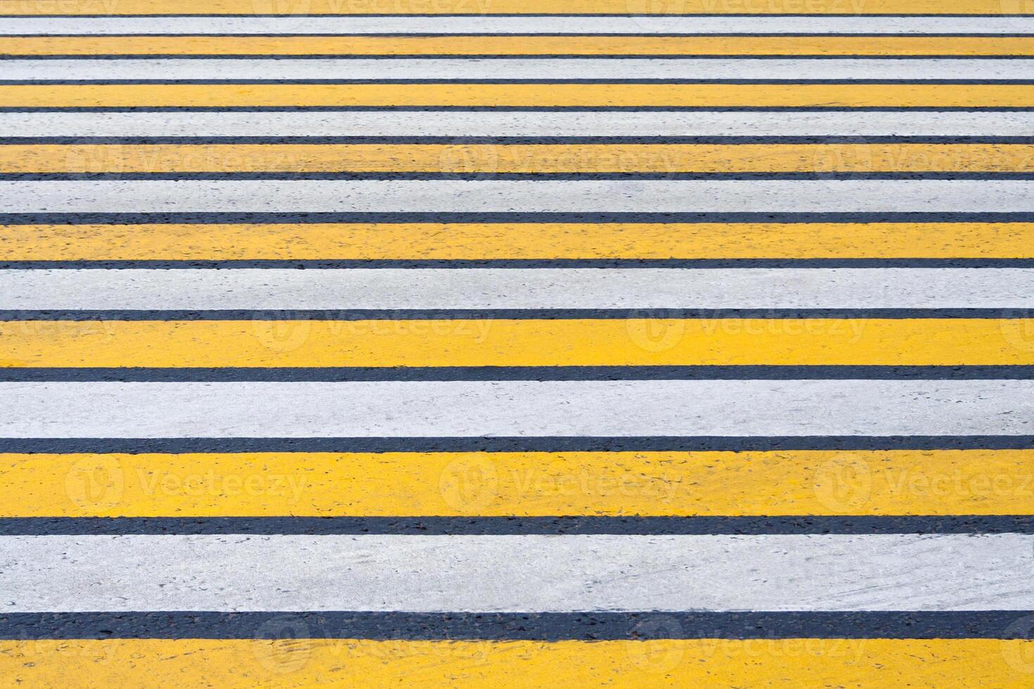 View of a yellow and white markings pedestrian lines on a asphalt road as background, texture photo