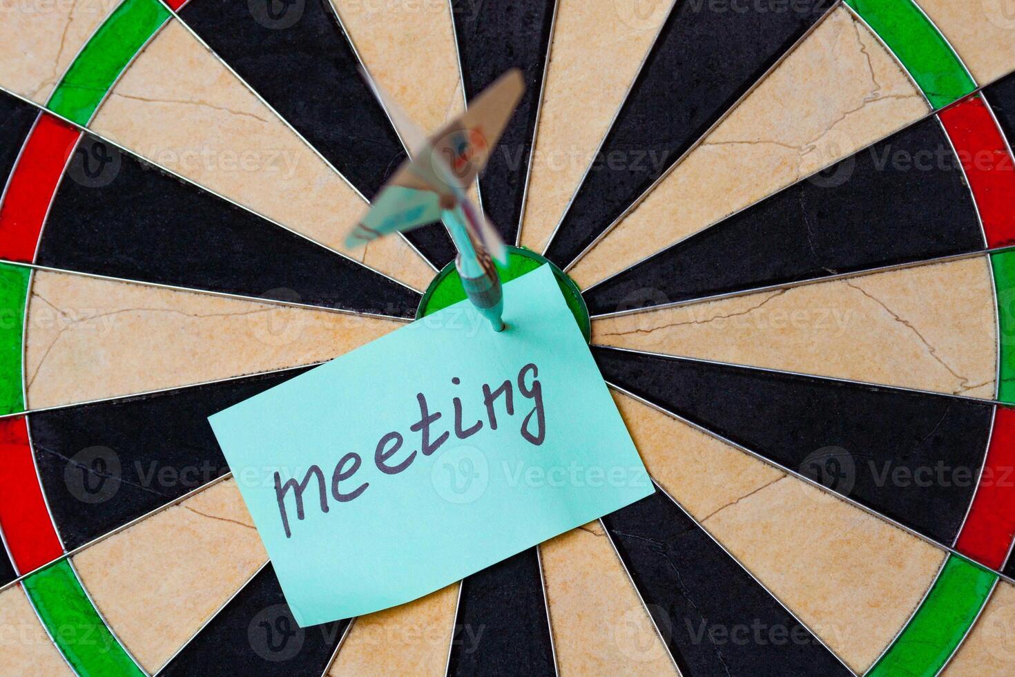 Dart hit the centre of target and attaches sticker with inscriptions meeting photo