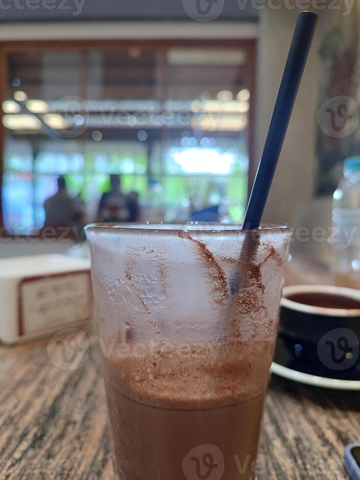 glass of iced chocolate tea served on wooden table in cafe. photo