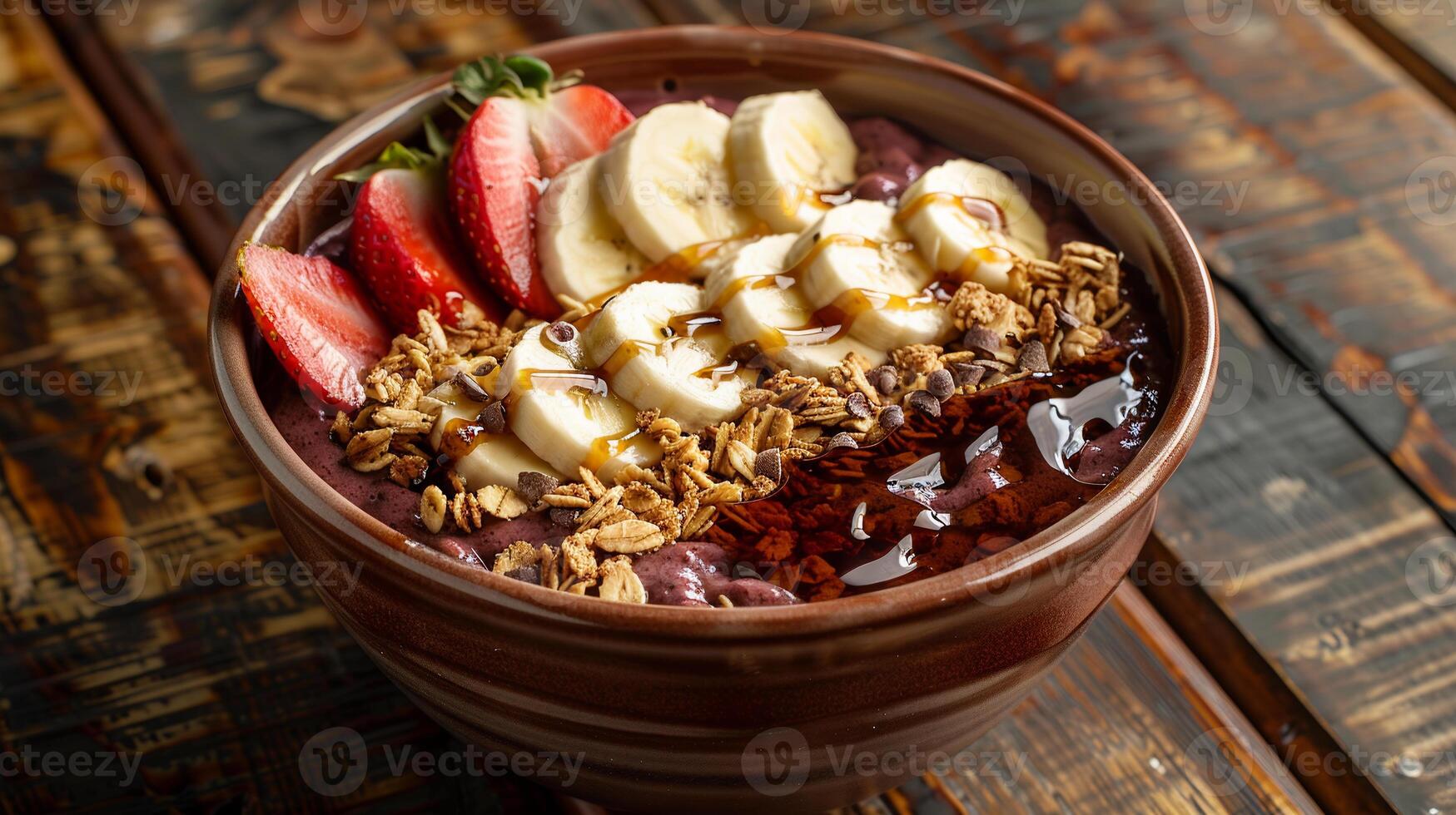 Acai bowl topped with granola, sliced bananas, strawberries, and a drizzle of honey. photo