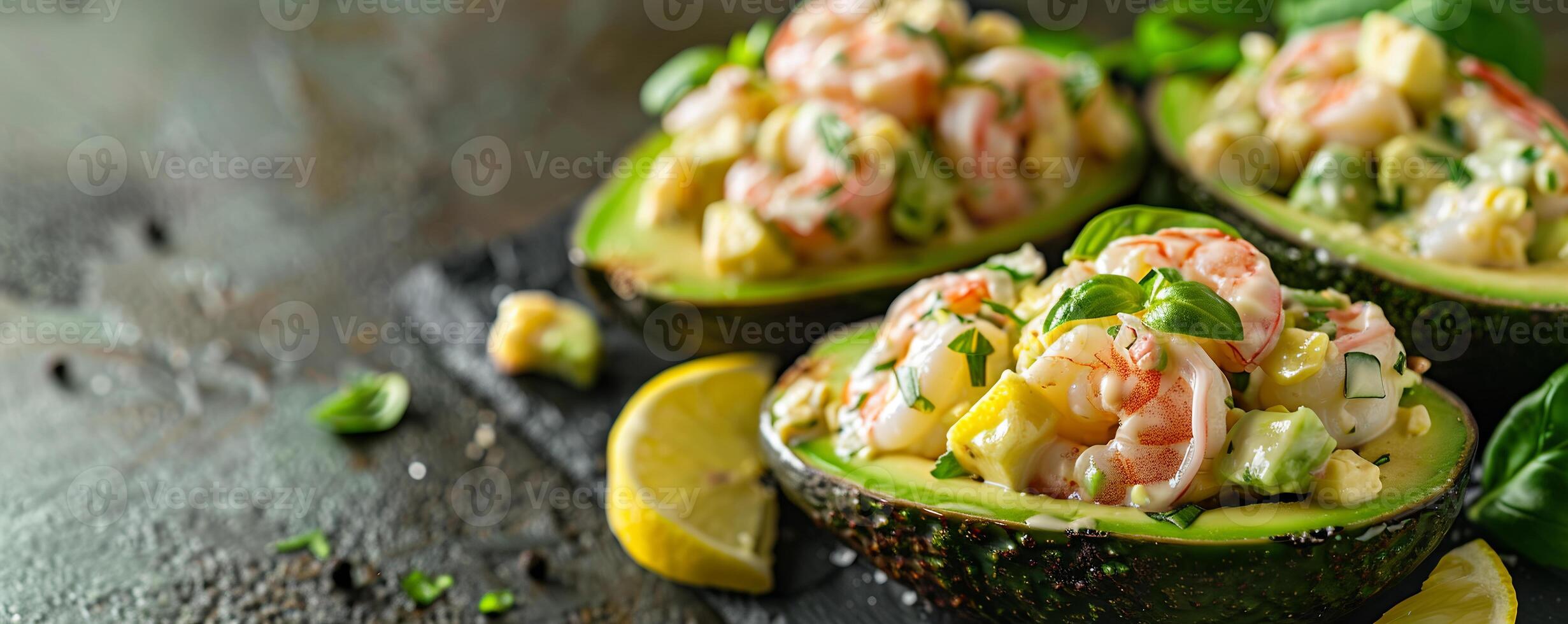 Avocado shrimp salad served in avocado halves with lemon wedges. photo