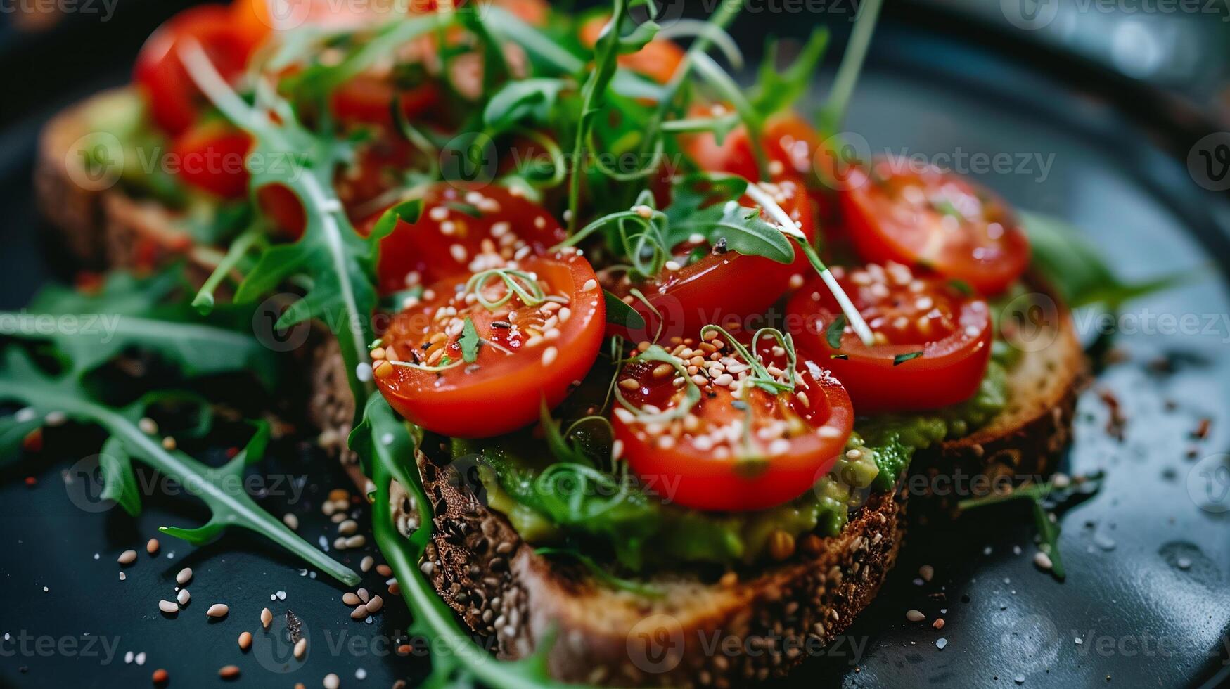 Whole grain avocado toast topped with cherry tomatoes, arugula, and a sprinkle of hemp seeds. photo