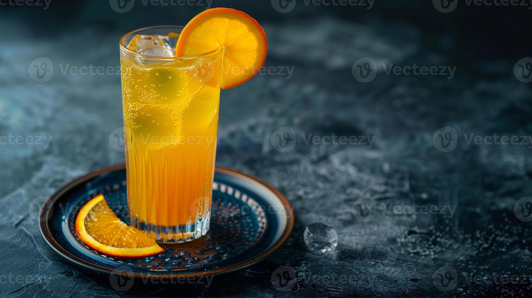 Tall glass of freshly squeezed orange juice with ice cubes and a slice of orange on the rim. photo
