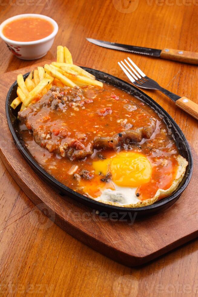 Rib eye steak and French fries with barbeque sauce photo