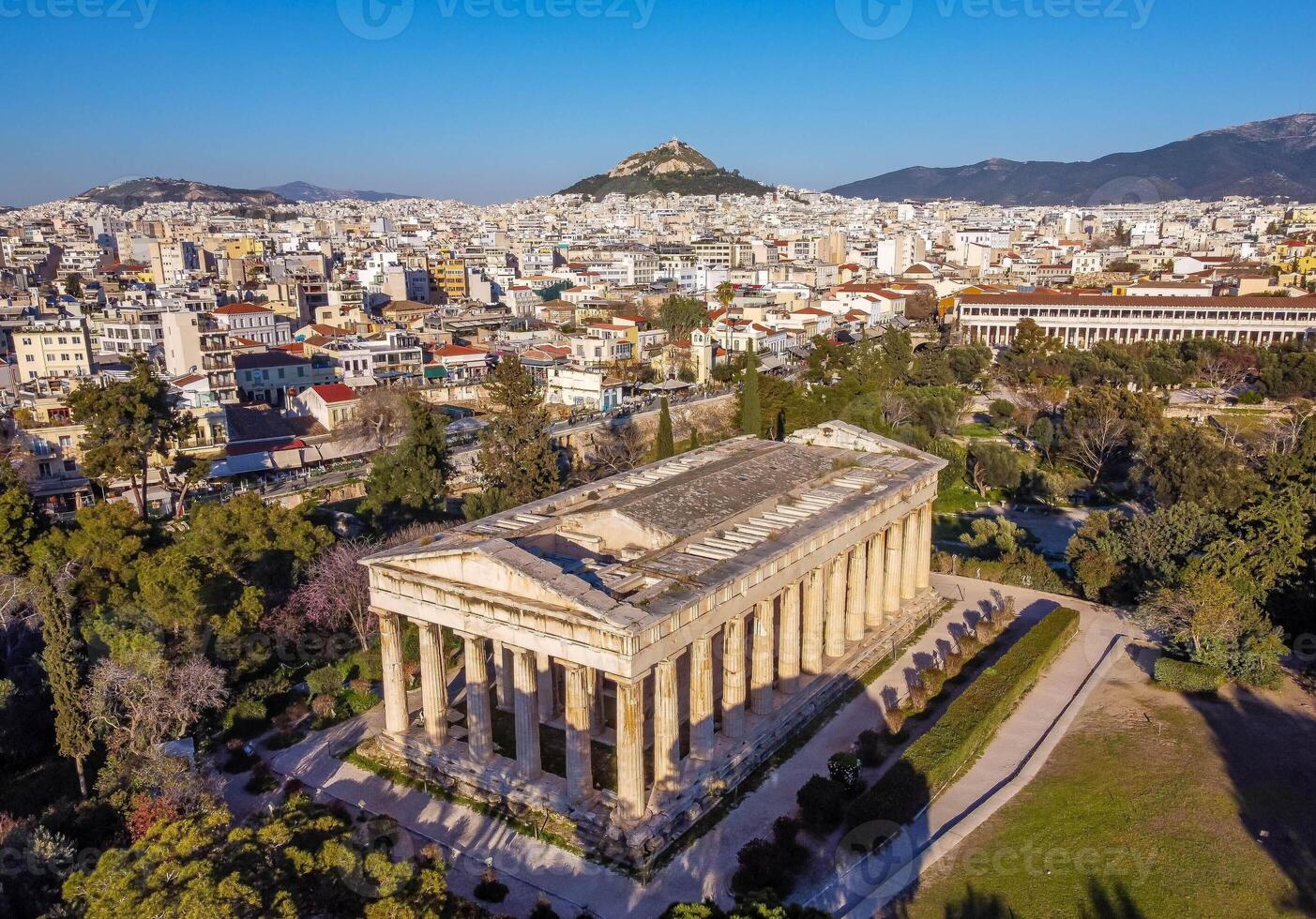 Temple of Hephaestus with the background of the city of Athens. Well-preserved artistic cultural heritage that attracts tourists in the summer period for a trip to discover the beauties of Greece. photo