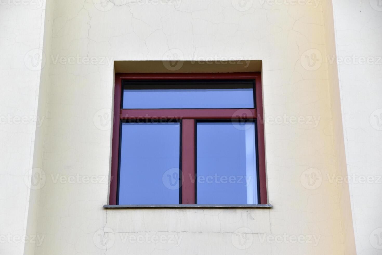 A red window on a yellow wall. A beautiful window in a classic building. photo