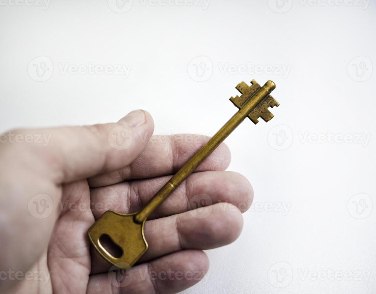 A copper key in his hand on a white background. The key to the front door. photo