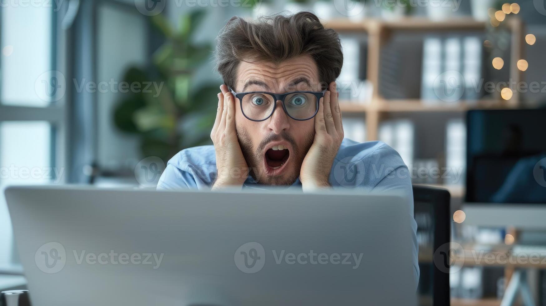 Man in Glasses Expresses Shock While Viewing Computer Screen photo
