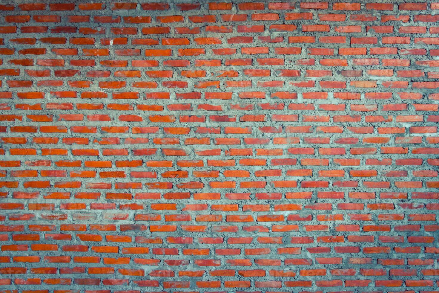 Red brick wall background with uneven texture and varying brick sizes. photo