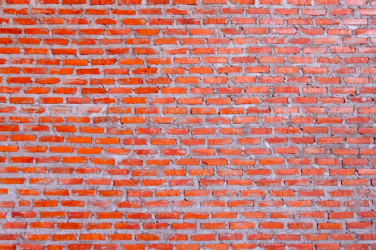 Red brick wall background with uneven texture and varying brick sizes. photo