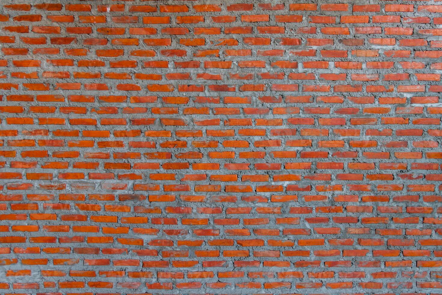 Red brick wall background with uneven texture and varying brick sizes. photo