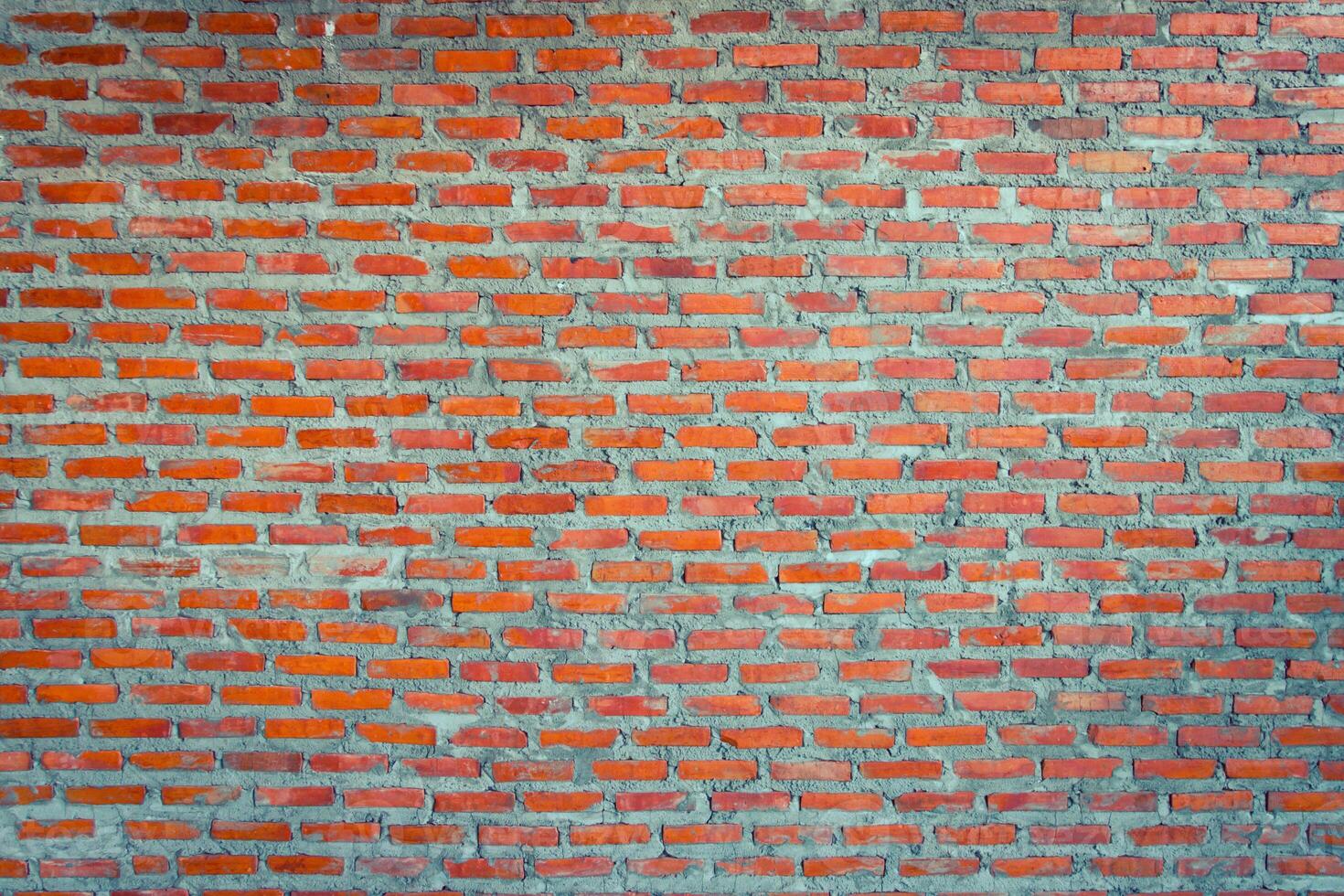 Red brick wall background with uneven texture and varying brick sizes. photo