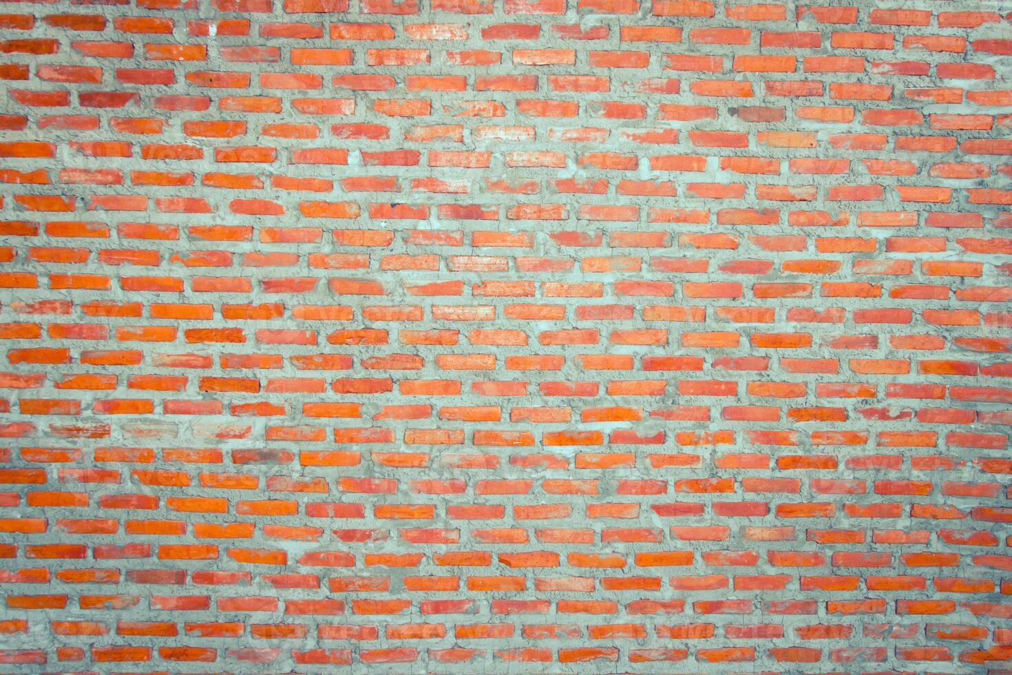 Red brick wall background with uneven texture and varying brick sizes. photo