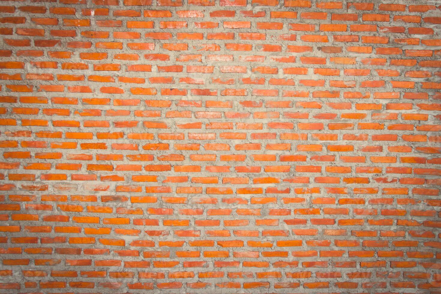 Red brick wall background with uneven texture and varying brick sizes. photo