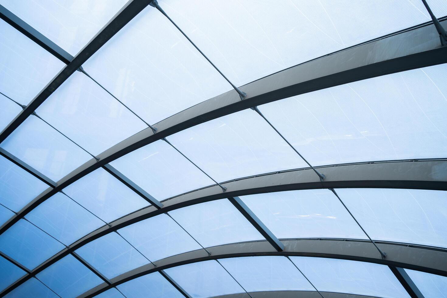 A large, curved glass structure with a blue tint. The glass is arranged in a way that creates a sense of depth and movement, giving the impression of a dynamic and ever-changing environment photo