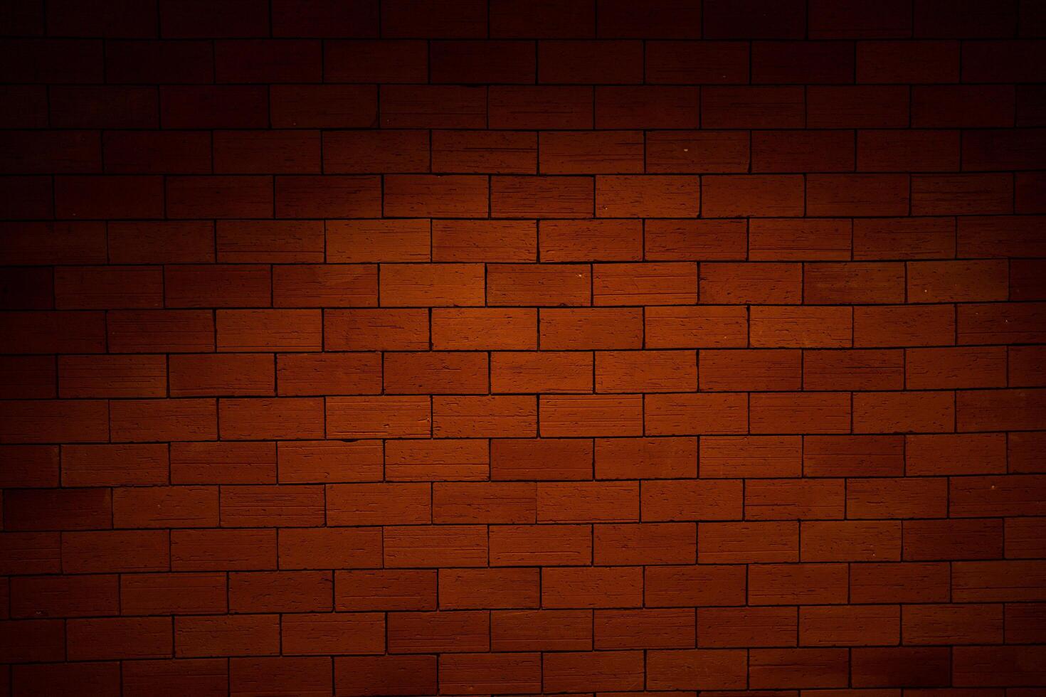 A brick wall with a dark brown color. The wall is made of bricks and has a rough texture photo