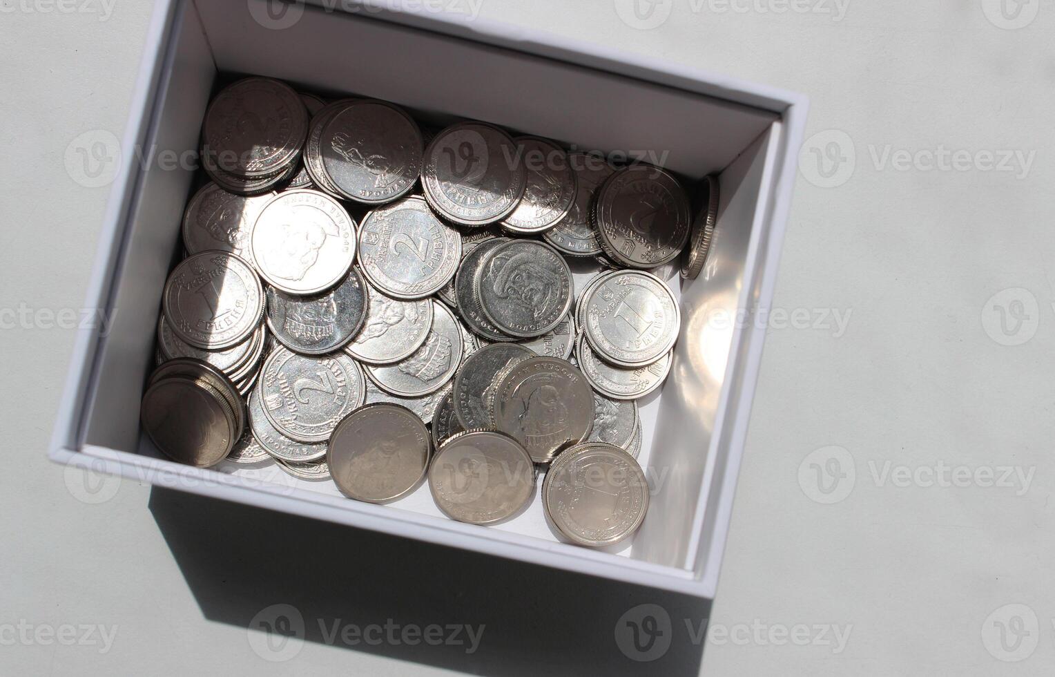 Ukrainian coins denomination 1 and 2 hryvnia in a cardboard box studio isolated stock photo