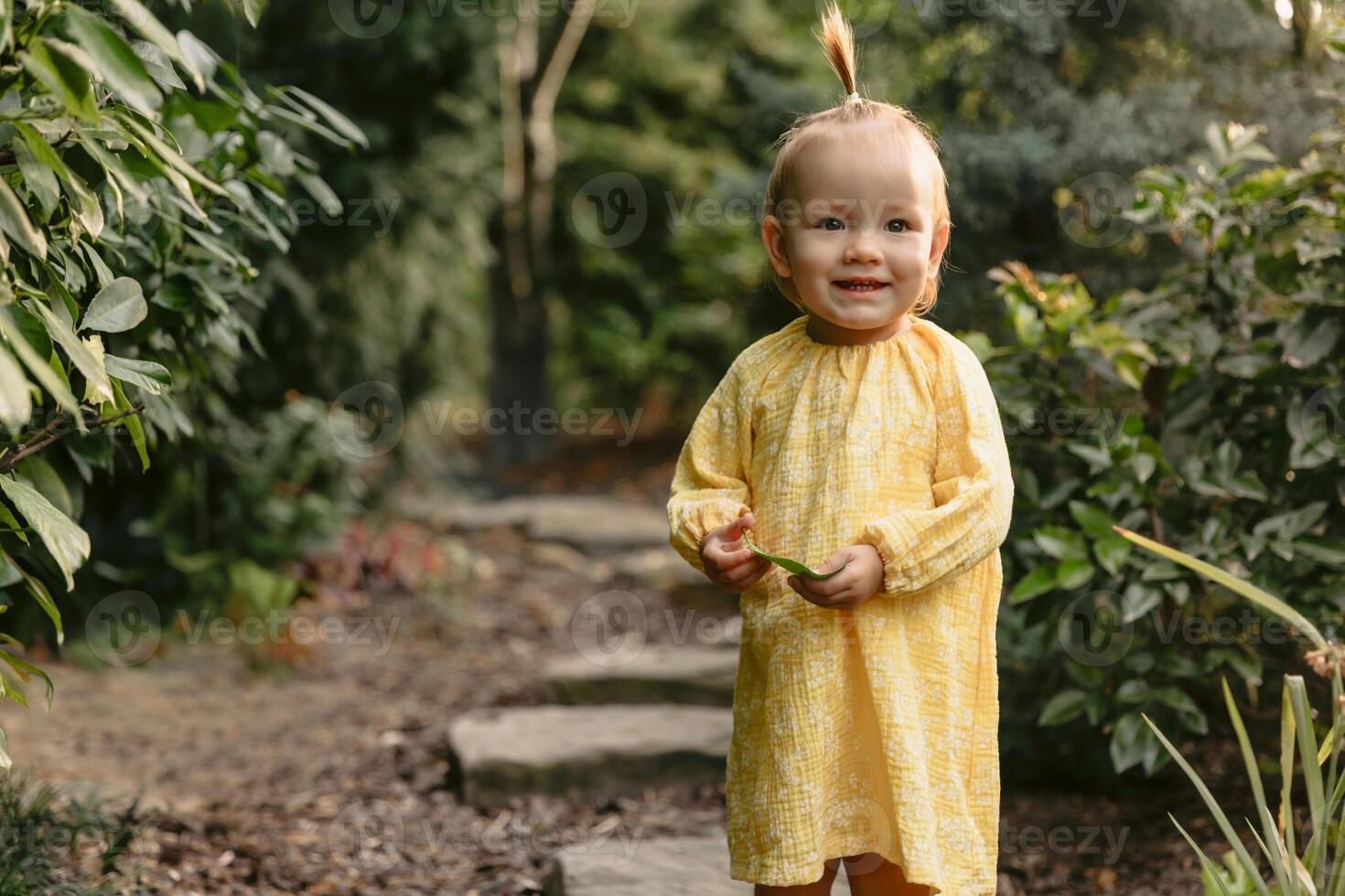 Smiling cute girl in stylish yellow dress in summer garden. photo