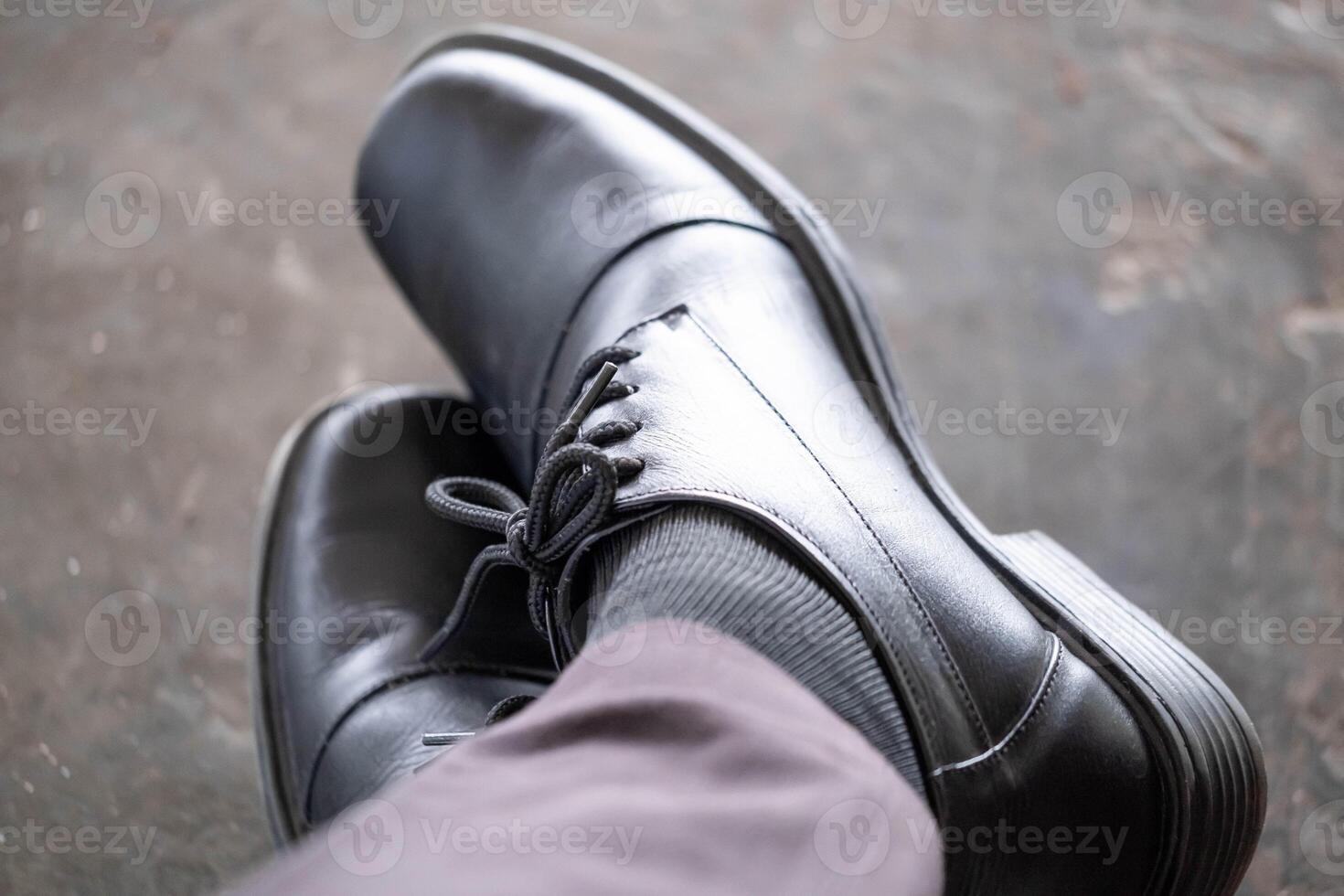 Close-up of black formal shoes and gray socks with legs crossed photo