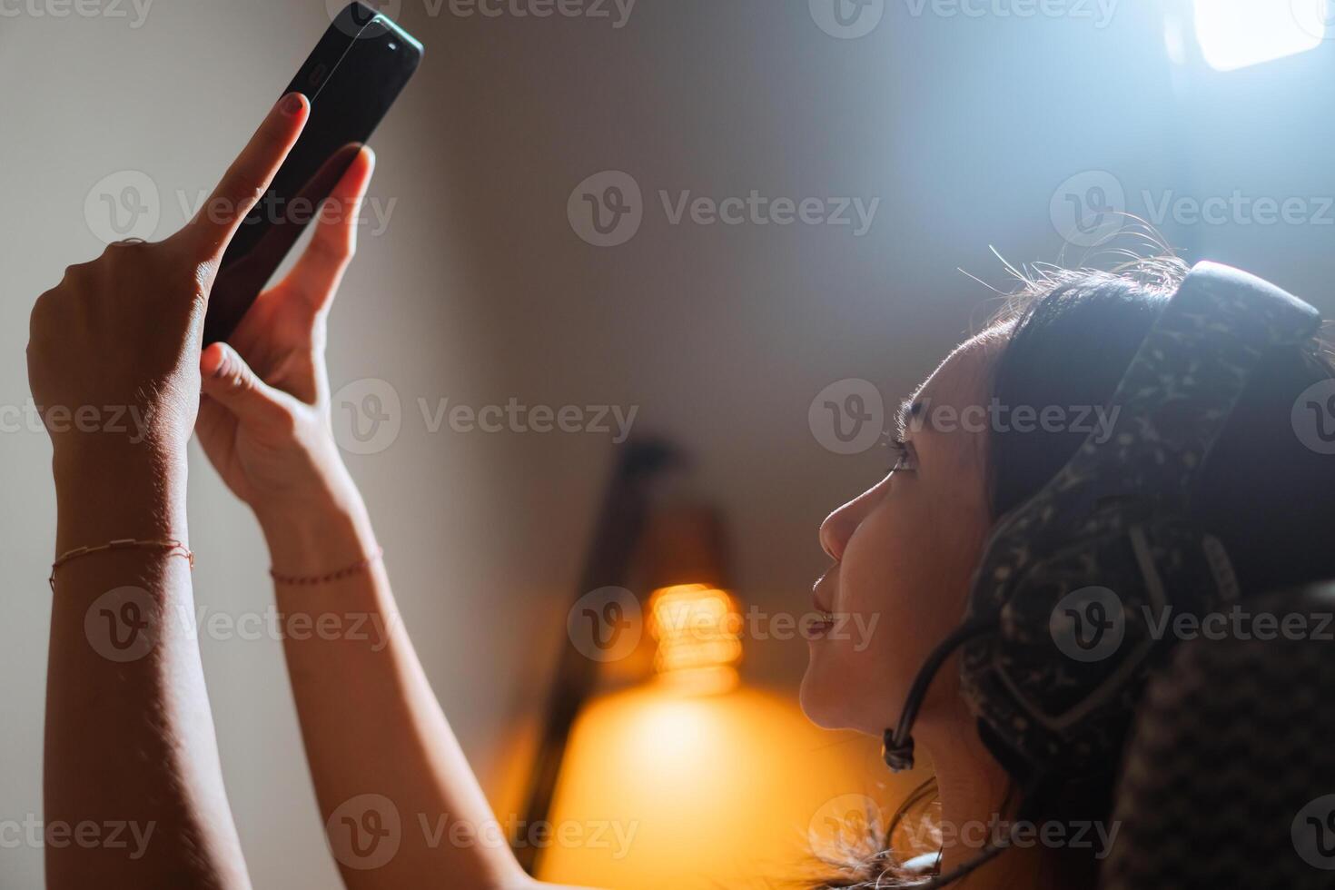 Woman taking a selfish with a smart phone in a dimly lit room photo