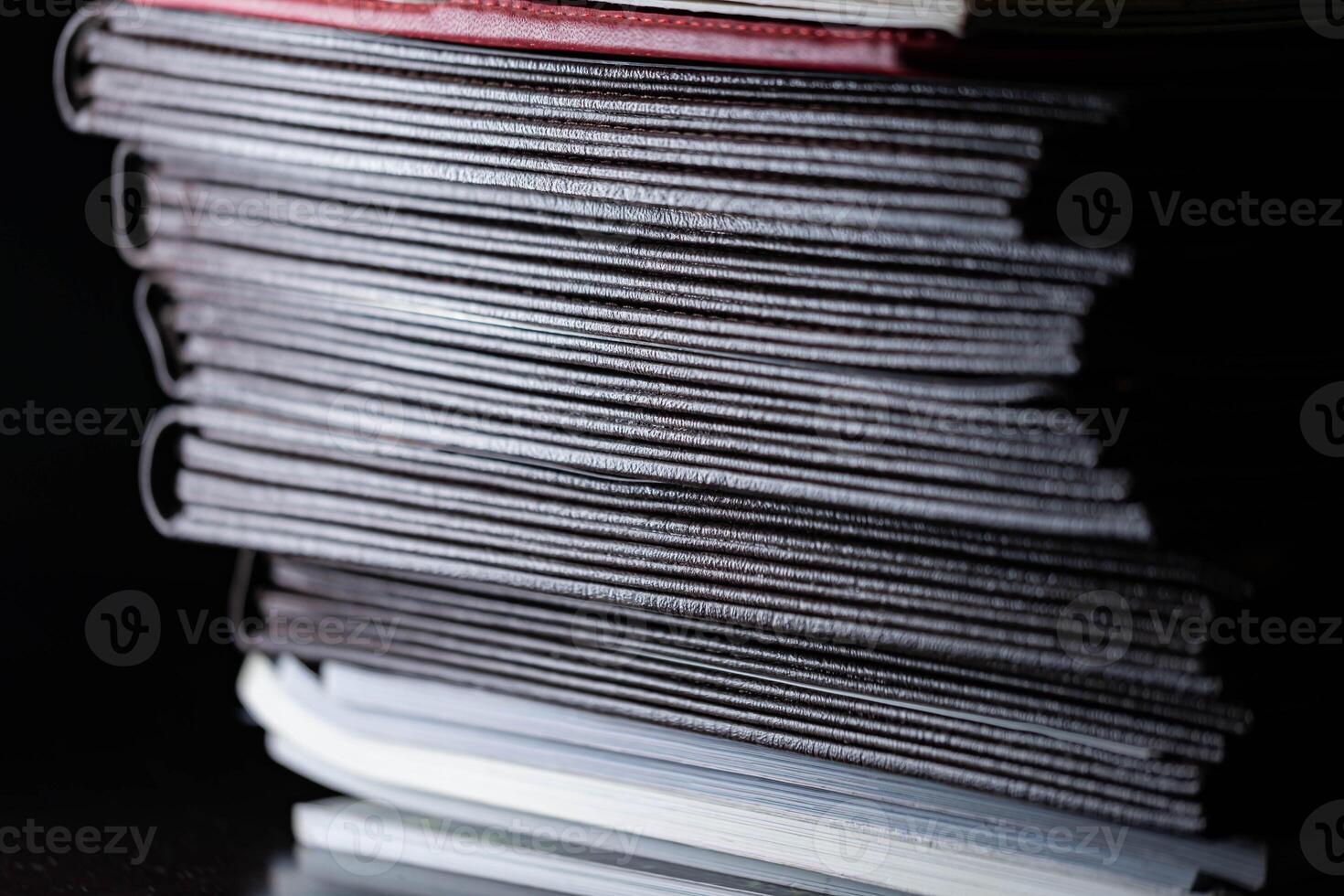 Close-up of a stack of dark-colored books in low light photo