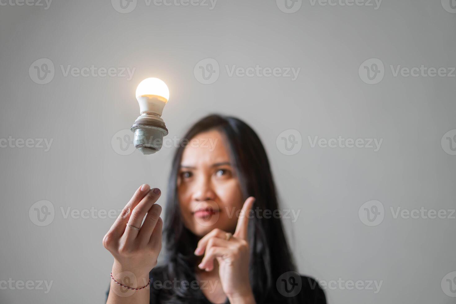 Woman pointing at floating glowing light bulb photo