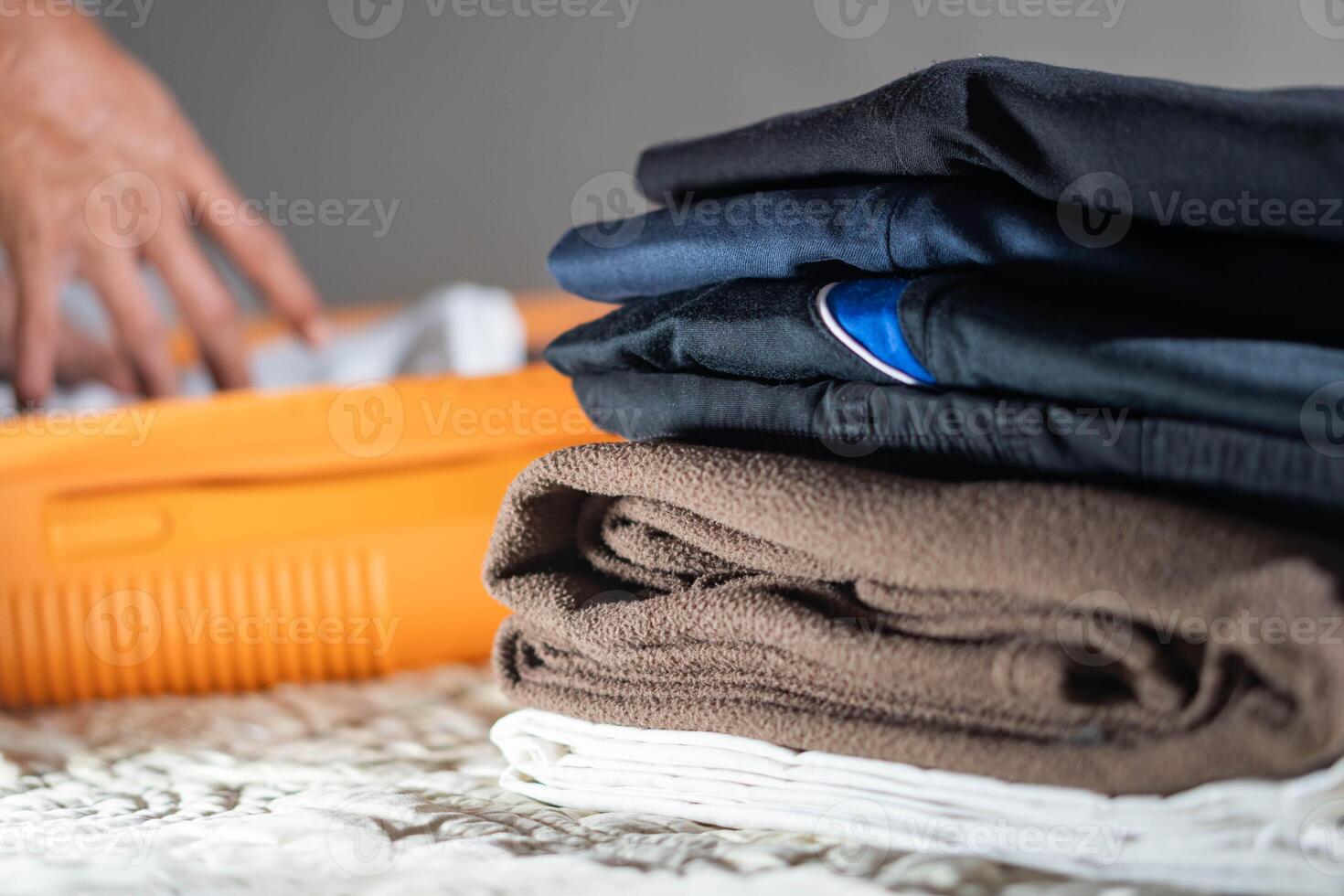 Packing suitcase with folded clothes on bed photo